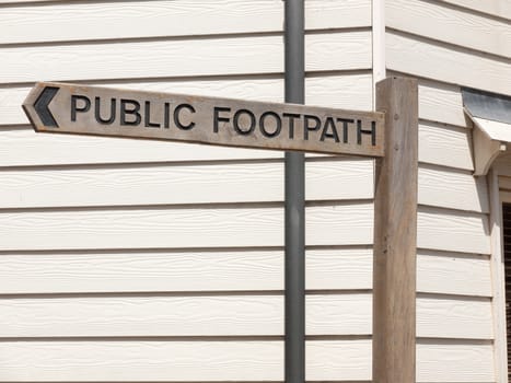a clear wooden post sign in town saying public footpath