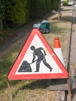 a triangle building in progress sign outside on ground metal