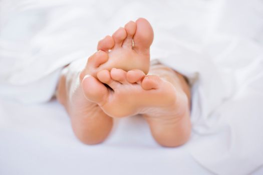 Naked feet in white sheets