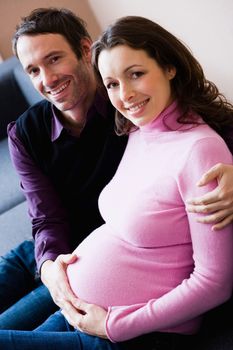 Pregnant woman and man sitting on couch
