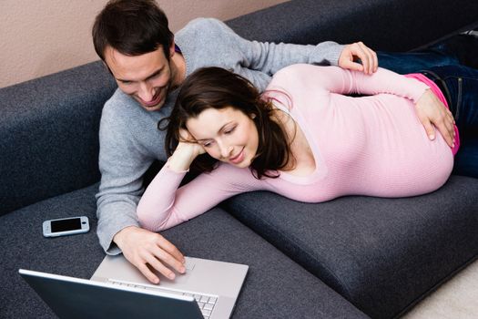 Pregnant woman and man laying on couch