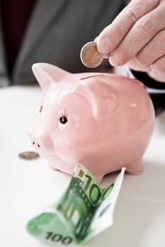 Hand putting coin into piggy bank