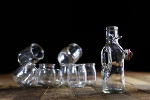 Glass empty containers on a wooden table. Jars, bottle. Black background