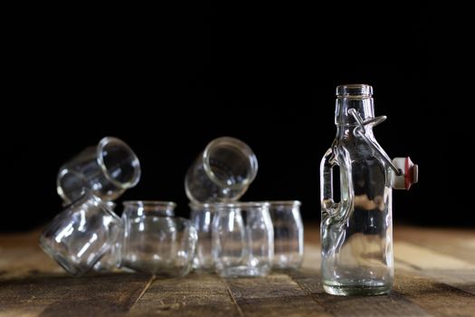 Glass empty containers on a wooden table. Jars, bottle. Black background