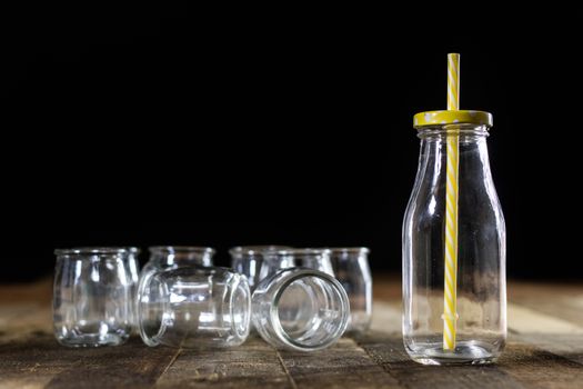 Glass empty containers on a wooden table. Jars, bottle. Black background