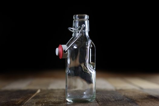 Glass empty containers on a wooden table. Jars, bottle. Black background