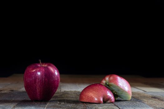 Red tasty wet apple on a wooden table. Black background.