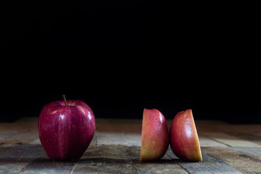 Red tasty wet apple on a wooden table. Black background.