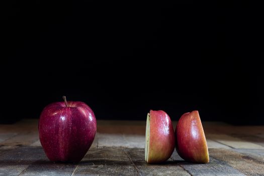 Red tasty wet apple on a wooden table. Black background.