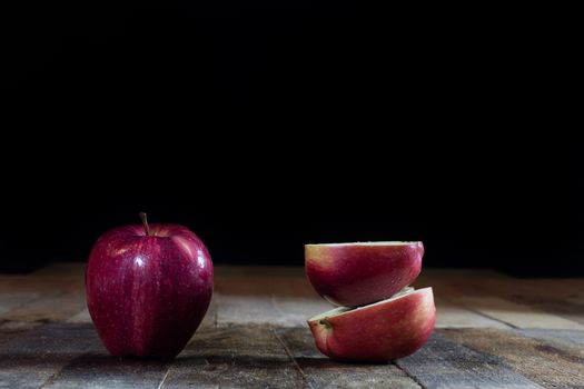 Red tasty wet apple on a wooden table. Black background.