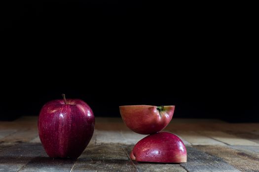 Red tasty wet apple on a wooden table. Black background.