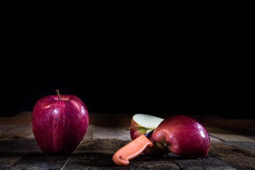 Red tasty wet apple on a wooden table. Black background.