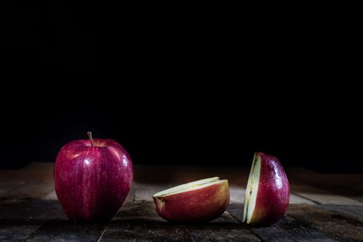 Red tasty wet apple on a wooden table. Black background.