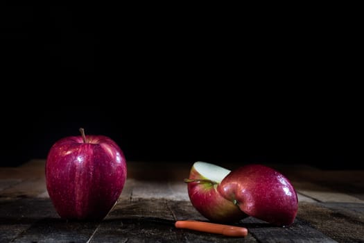 Red tasty wet apple on a wooden table. Black background.