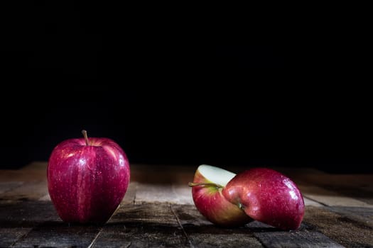 Red tasty wet apple on a wooden table. Black background.