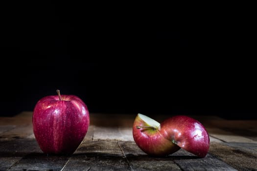 Red tasty wet apple on a wooden table. Black background.