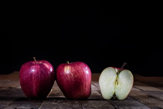 Red tasty wet apple on a wooden table. Black background.