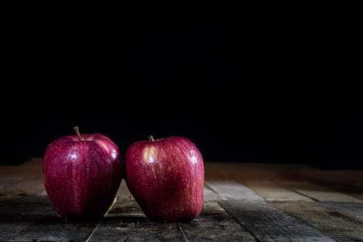 Red tasty wet apple on a wooden table. Black background.