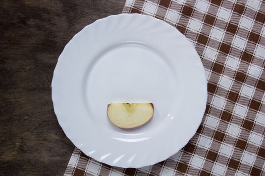 White plate with a slice of apple on a wooden table