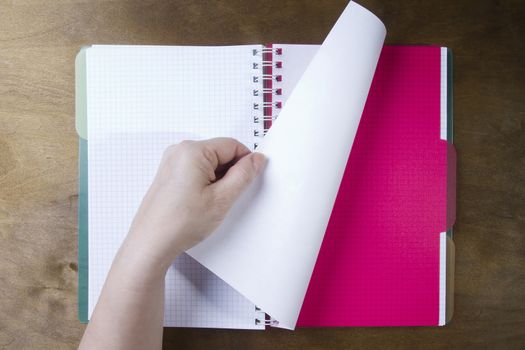 Hands flipping page notebooks on a wooden table