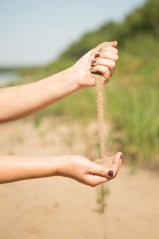 sand running through hands of woman in the beach