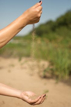 sand running through hands of woman in the beach