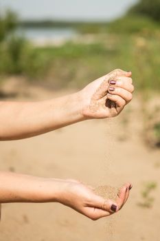 sand running through hands of woman in the beach