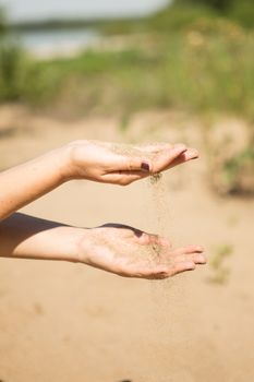 sand running through hands of woman in the beach