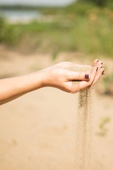 sand running through hands of woman in the beach