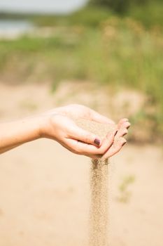 sand running through hands of woman in the beach