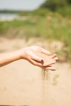 sand running through hands of woman in the beach