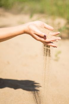 sand running through hands of woman in the beach