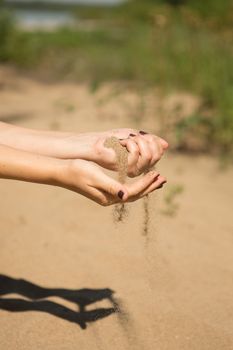 sand running through hands of woman in the beach