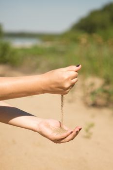 sand running through hands of woman in the beach