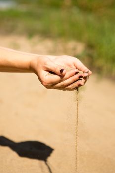 sand running through hands of woman in the beach