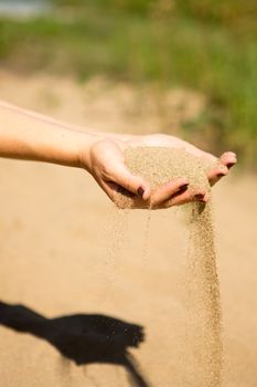 sand running through hands of woman in the beach