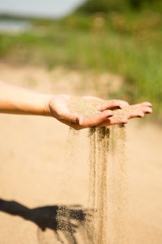 sand running through hands of woman in the beach