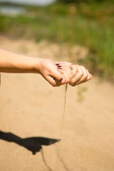 sand running through hands of woman in the beach