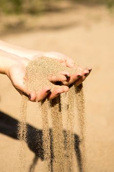 sand running through hands of woman in the beach