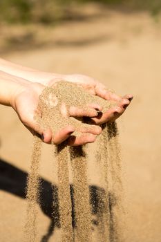 sand running through hands of woman in the beach