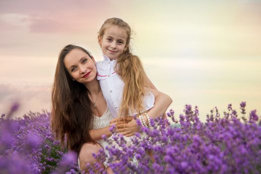 Mother with daughter on the lavender field at sunset