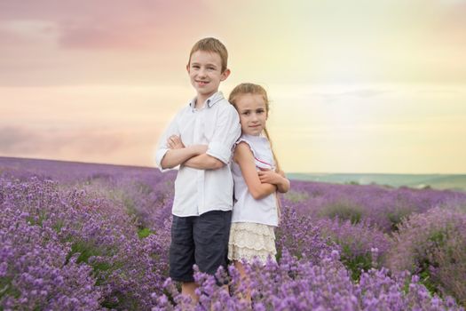 Happy brother and sister in lavender summer field back-to-back