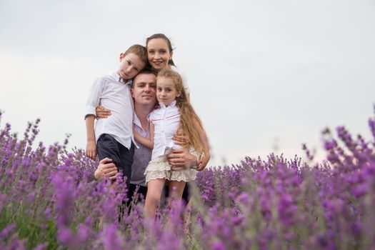 Happy family of four in lavender field over white