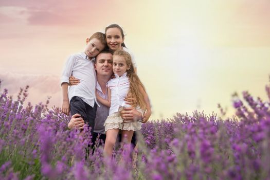 Happy family of four in lavender field at sunset