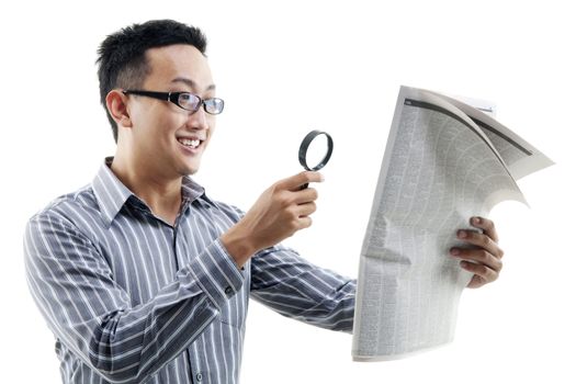 Excited Asian man reading newspaper with magnifier glass, isolated on white background