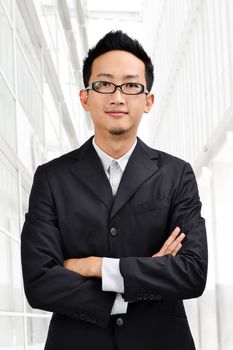 Asian businessman in full suit standing in front modern building.