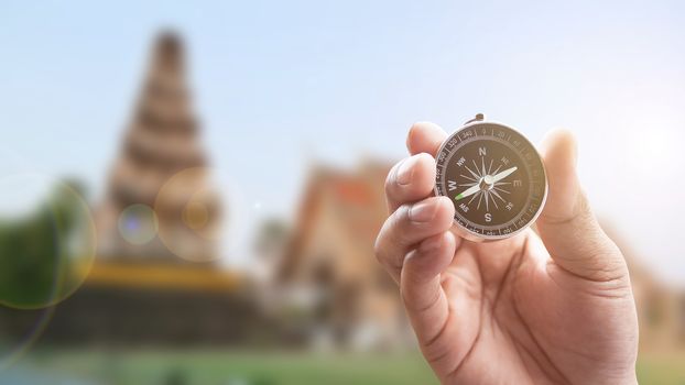 compass in hand on thai temple blur background with lighting flare