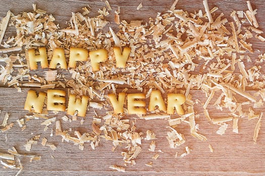 Happy new year text with bread and saw dust on wooden background