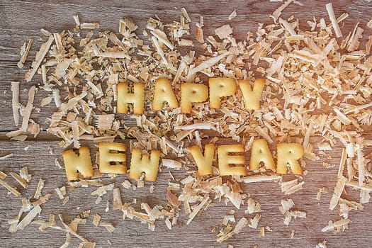 Happy new year text with bread and saw dust on wooden background
