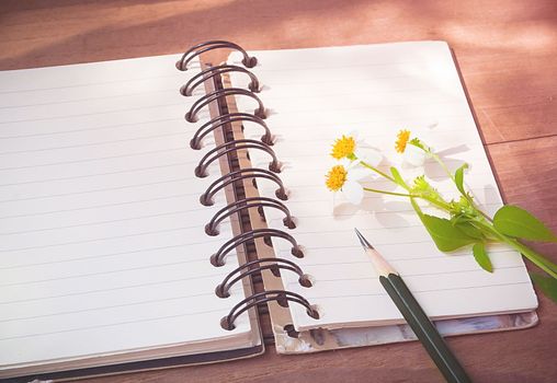 Empty page of notebook on desk, Black pencil and flower on notebook, Space for text, Vintage style